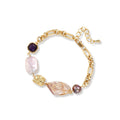 Gold-plated chain bracelet with mixed gemstones including purple stone, baroque pearl, and clear crystal on neutral background.